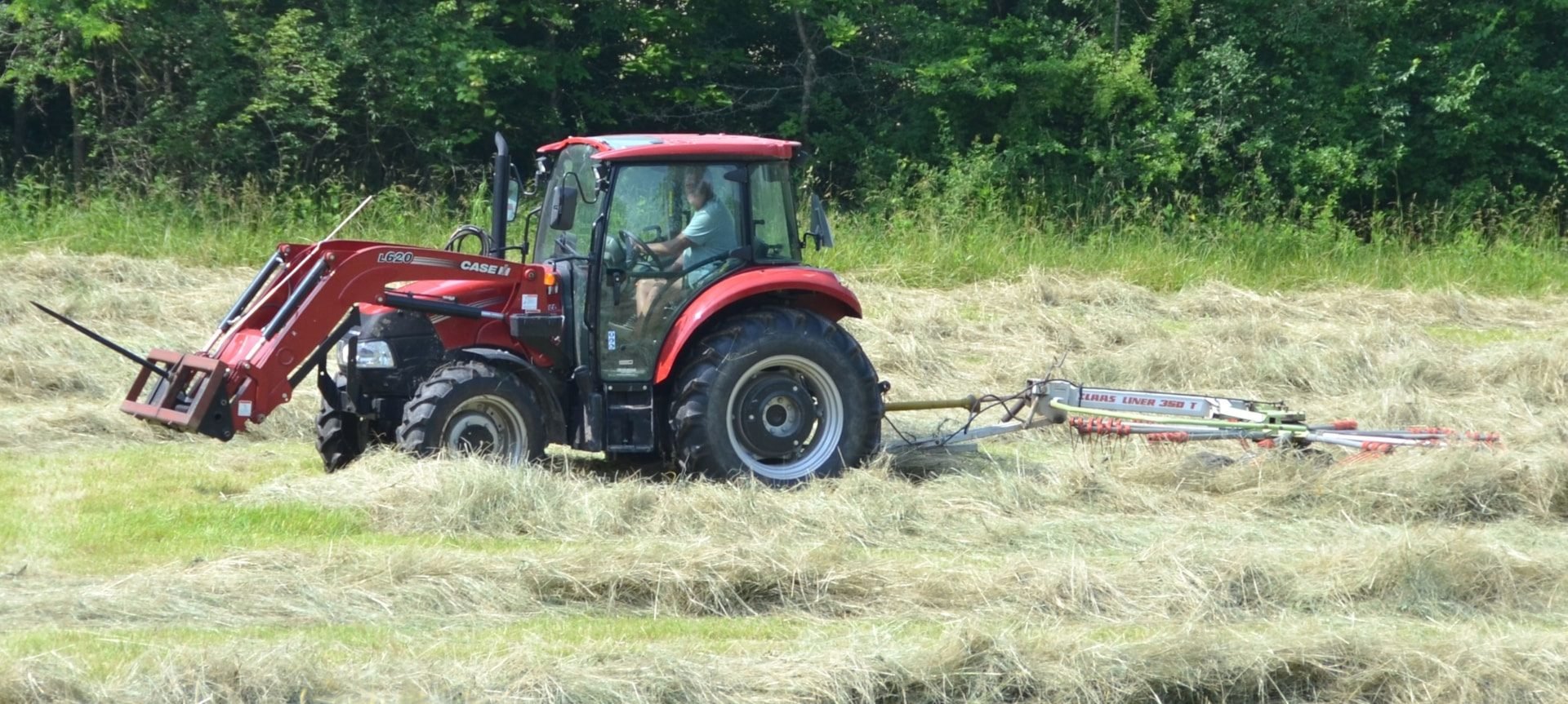 Case IH tractor raking hay